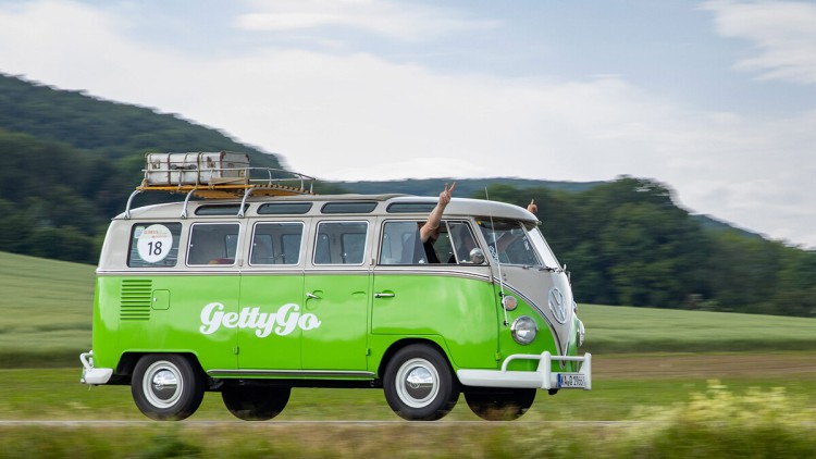 Grüner VW Bulli von GETTYGO fährt durch eine Sommerlandschaft