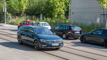 VW Passat Kombi in blaumetallic fahrend schraeg von vorn auf Strasse