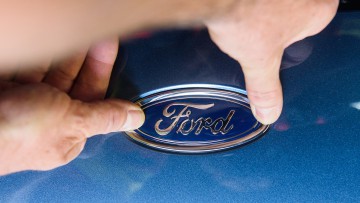 Ein Ford-Logo wird im Werk Saarlouis an einen Focus angebracht