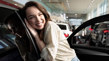 Eine Frau schmiegt sich in einem Showroom an ein Auto