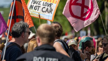 Ein Schild mit der Aufschrift «Make love not car» ist neben Fahnen von Extinction Rebellion bei der Abschlussdemonstration gegen die Automesse IAA MOBILITY 2023 zu sehen.