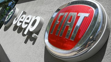 Markenlogos von Alfa Romeo, Jeep und Fiat an einer Hauswand