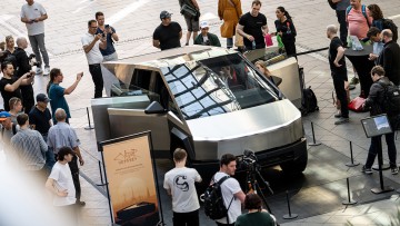 Menschen stehen bei der Vorstellung des Tesla Cybertrucks in der Mall of Berlin zum Auftakt von "The Cyber Odyssey" um das Auto. 
