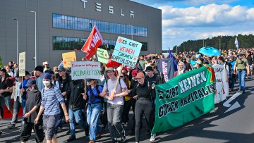 Teilnehmer einer Protestveranstaltung gehen zum Werk von Tesla. Nach teils heftigen Auseinandersetzungen am 10.05.2024 am Tesla-Werksgelände in Grünheide bei Berlin stellt laufen derzeit neue Proteste gegen das US-Unternehmen.