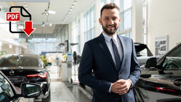 Lächelnder Automobilverkäufer steht im Showroom vor Neufahrzeugen