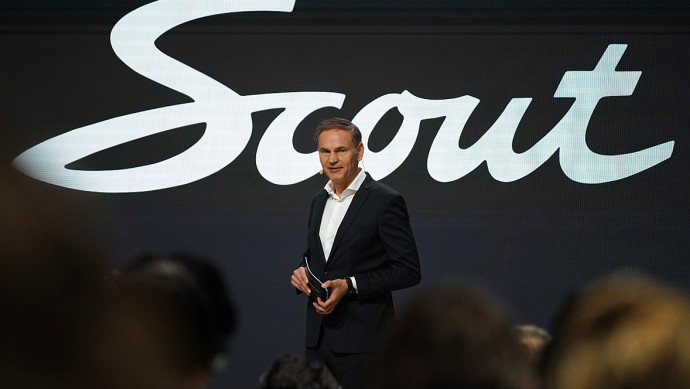 VW-Chef Oliver Blume vor einem Logo der neuen Marke Scout