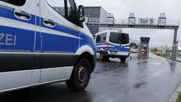 Einsatzfahrzeuge der Polizei stehen an einem Werk von Mercedes-Benz.