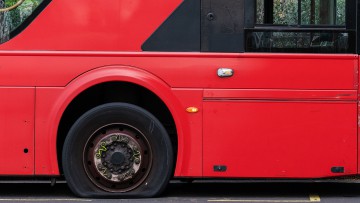 Roter Reisebus, der einen platten Reifen hat
