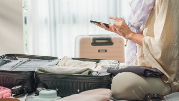Reisende mit gepacktem Koffer auf einem Hotelbett