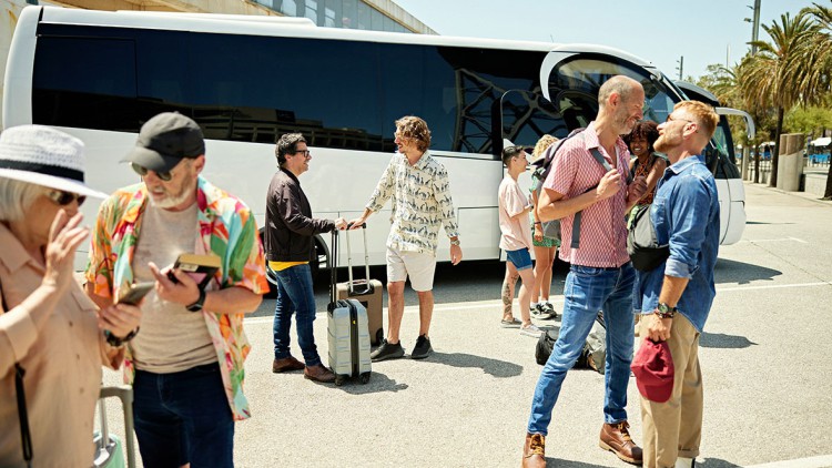 Busreisegäste vor einem weißen Reisebus in Spanien