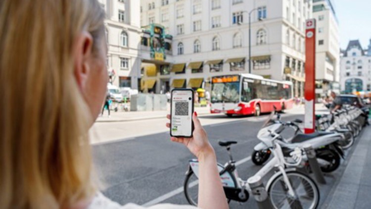 Frau mit Smartphone in Wien zur Einführung des digitalen Tickets bei den Wiener Linien - im Hintergrund ein Linienbus 