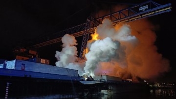 Brandqualm über nächtlichem Containerschiff