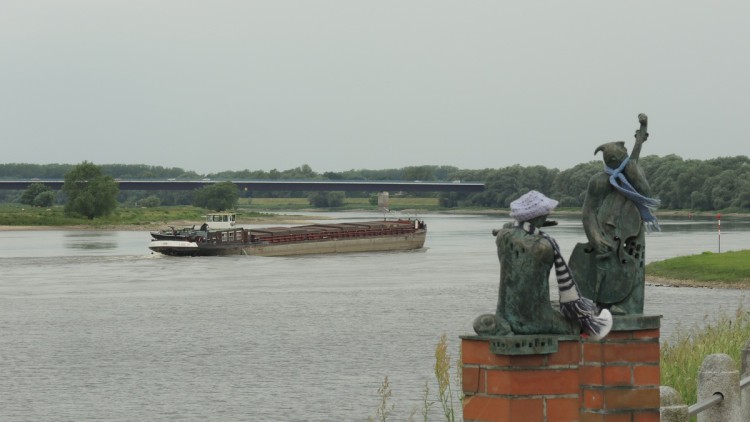 Ein Frachter auf einem Fluss und zwei Skulpturen