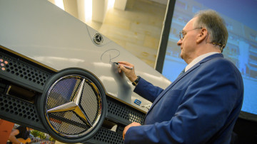 Reiner Haseloff (CDU) unterschreibt während einer Projektvorstellung zur Standortentscheidung von Daimler Truck in Halberstadt den Kühlergrills eines Lastwagens