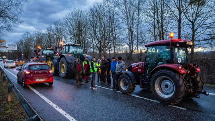 Landwirte blockieren in der Dämmerung mit ihren Traktoren und Fahrzeugen die Straße 
