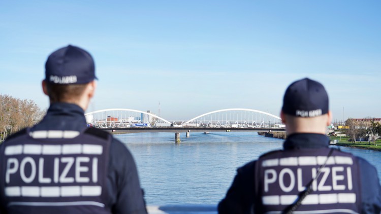 Zwei Polizisten blicken am deutsch-französischen Grenzübergang in Kehl von der Passrelle des Deux Rives in Richtung Europabrücke, wo sich der Verkehr staut. 