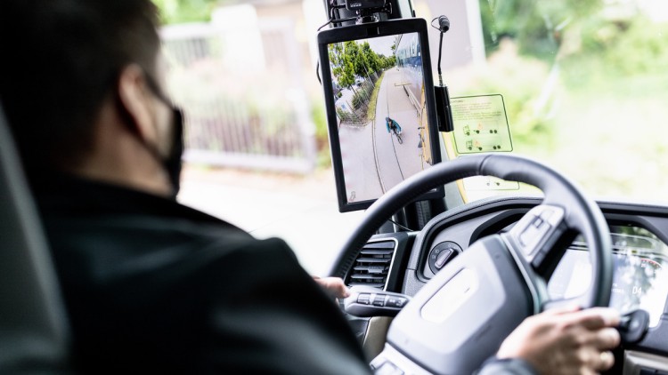 Lkw-Fahrer sieht auf Bildschirm eine Person im toten Winkel des Fahrzeugs 