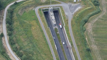 Luftaufnahme zeigt wie ein LKW und Autos, bei Dedesdorf in den Wesertunnel fahren.