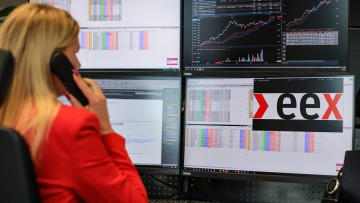 Eine Mitarbeiterin  der Europäischen Energiebörse EEX arbeitet in einem rotem Jackett in der Marktsteuerung (Market Operation).