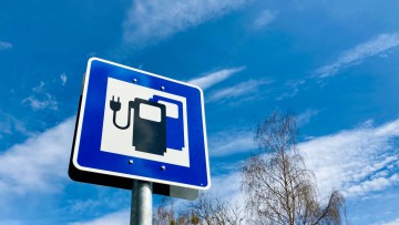 Schild vor blauem Himmel für Schnellladesäule an einer Straße für E-Fahrzeuge zum Aufladen von Batterien