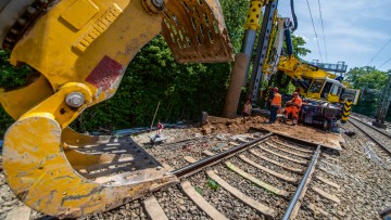 Schienen, Schwellen, Oberleitungen: Handwerker mit schweren Maschinen auf einer Bahn-Baustelle 