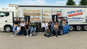 Das weibliche Team der Topregal GmbH vor einem Lkw und in zwei Gabelstaplern