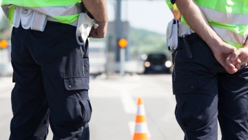 Die Beine von zwei Polizisten bei einer Verkehrskontrolle auf der Autobahn