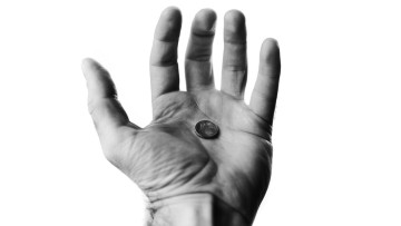 Ausgestreckte Hand hält eine einzelne Münze