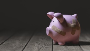 Zerbrochenes Sparschwein mit Pflasterverband oder Gipsfinanzierung Hintergrundkonzept für wirtschaftliche Rezession oder Insolvenz