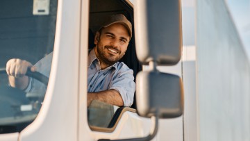 Glücklicher LKW-Fahrer, der durch das Seitenfenster seines Fahrzeugs schaut