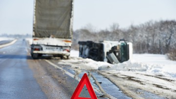 Warndreieck vor einem Lkw-Unfall auf einer verschneiten Straße