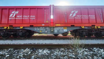Ein neuer Intermodalwagen mit zwei Containern, die das Mercitalia-Rail-Logo tragen, steht auf einem Gleis.