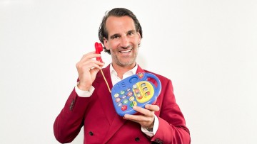 Ein Mann im Roten Anzug telefnoiert mit einem Spielzeug-Telefon