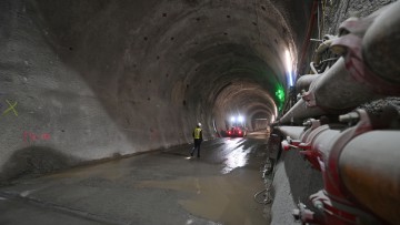 Beim Bau des Brennerbasistunnels (BBT) wird in einer der Hauptröhren gearbeitet. Blick in die Röhre, in einiger Entfernung sieht man einen Arbeiter und ein Fahrzeug.