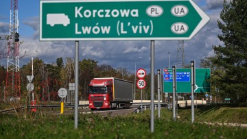 Ein Schild weist zur Lkw-Abfahrt des polnisch-ukrainischen Grenzübergangs Korczowa. Im Hintergrund eine Straße mit einem Lkw und weitere Schilder