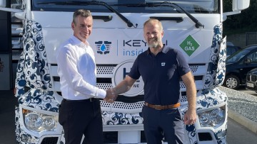 Die Geschäftsführer Berhard Wasner vom Unternehmen Josef Paul (links) und Markus Schneider von Keyou (rechts) reichen sich vor einem Wasserstoff-Lkw die Hand