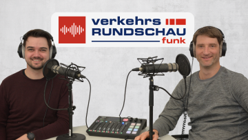 Fabian Faehrmann und Jan Burgdorf mit Kopfhörern vor Schriftzug VerkehrsRundschau Funk
