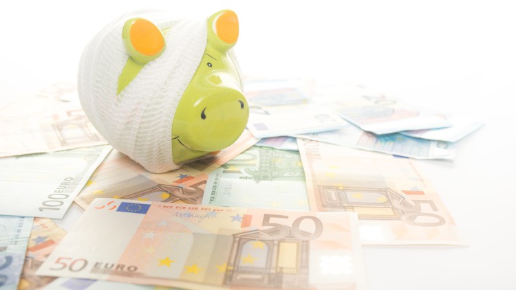 Ein „krankes“ Sparschwein – mit einem Verband umwickelt – steht auf Geldscheinen. Symbolbild für Krankengeld